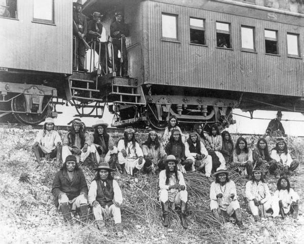 Black and white photo of the Chiricahua Apache in front of a train as prisoners of war.