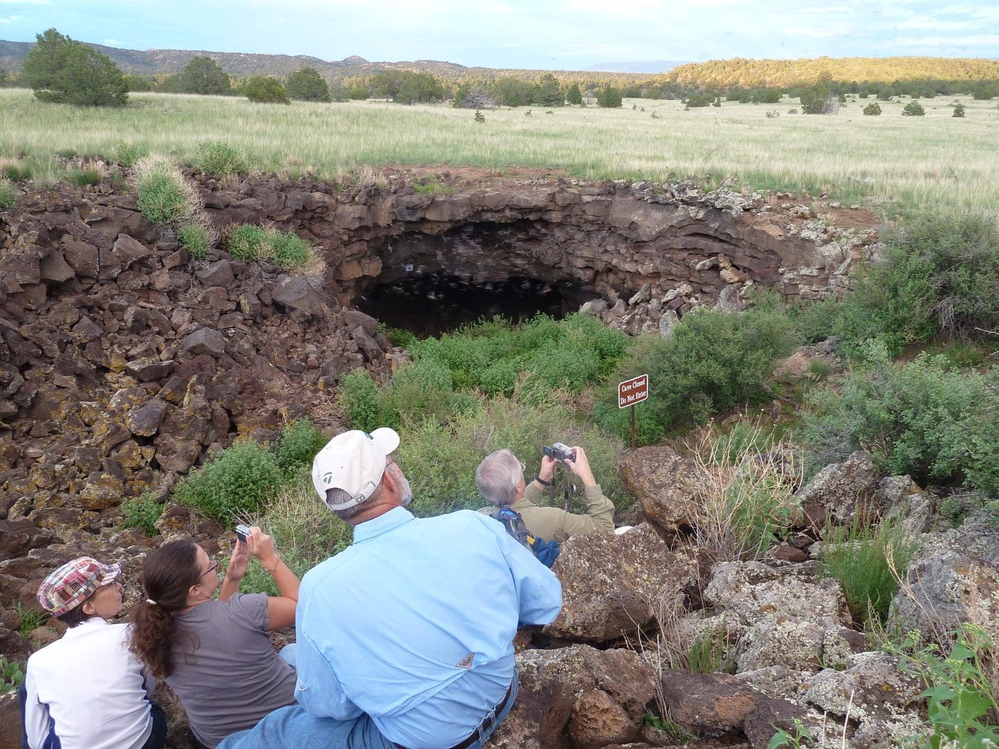 Four visitors, two with cameras, watch bats edit El Calderon cave in El Malpais National Monument