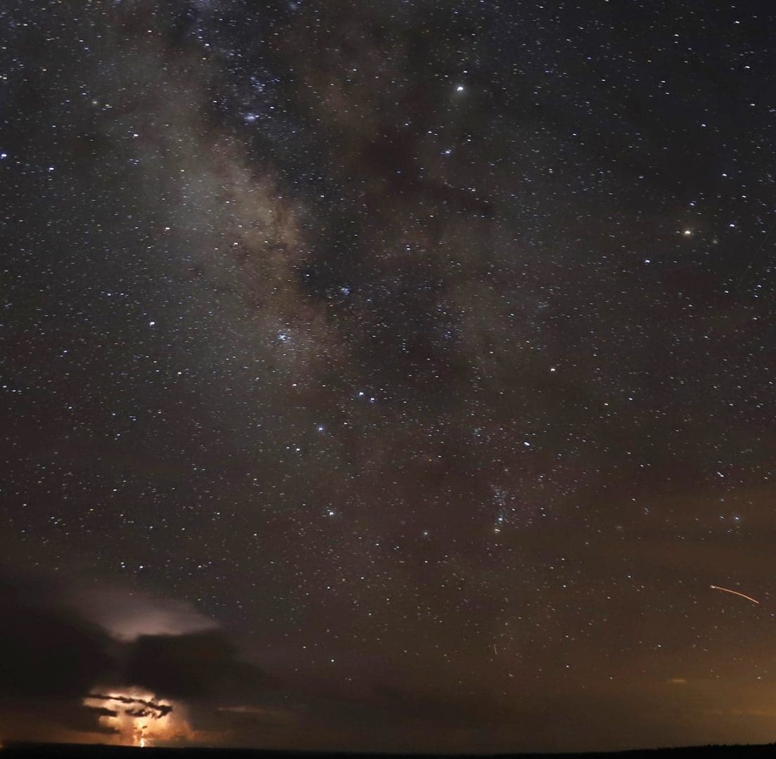 The milky way in a dark sky with lightning strike