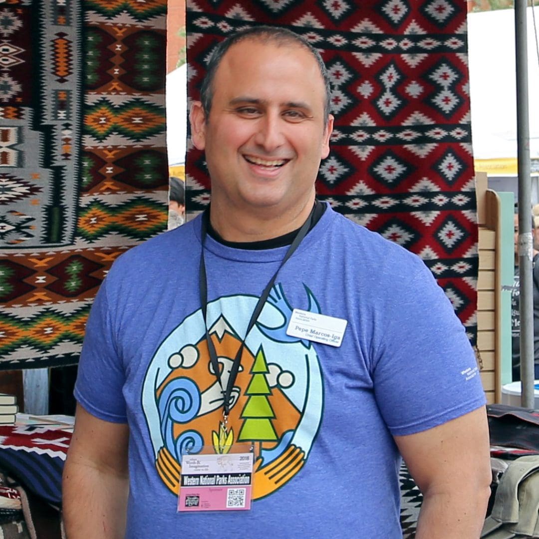 Color photograph of Pepe Marcos-Iga at the Tucson Festival of Books, in front of Navajo rugs