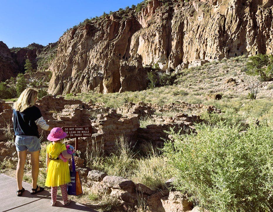 Woman and child looking up at Bandelier National Monument.
