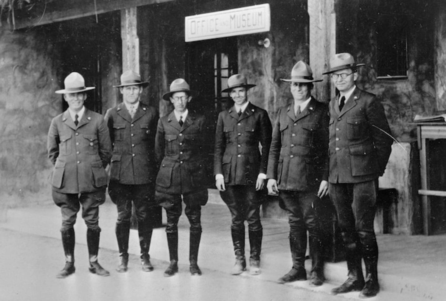 Black and white photo of six park rangers in uniform standing in a row.