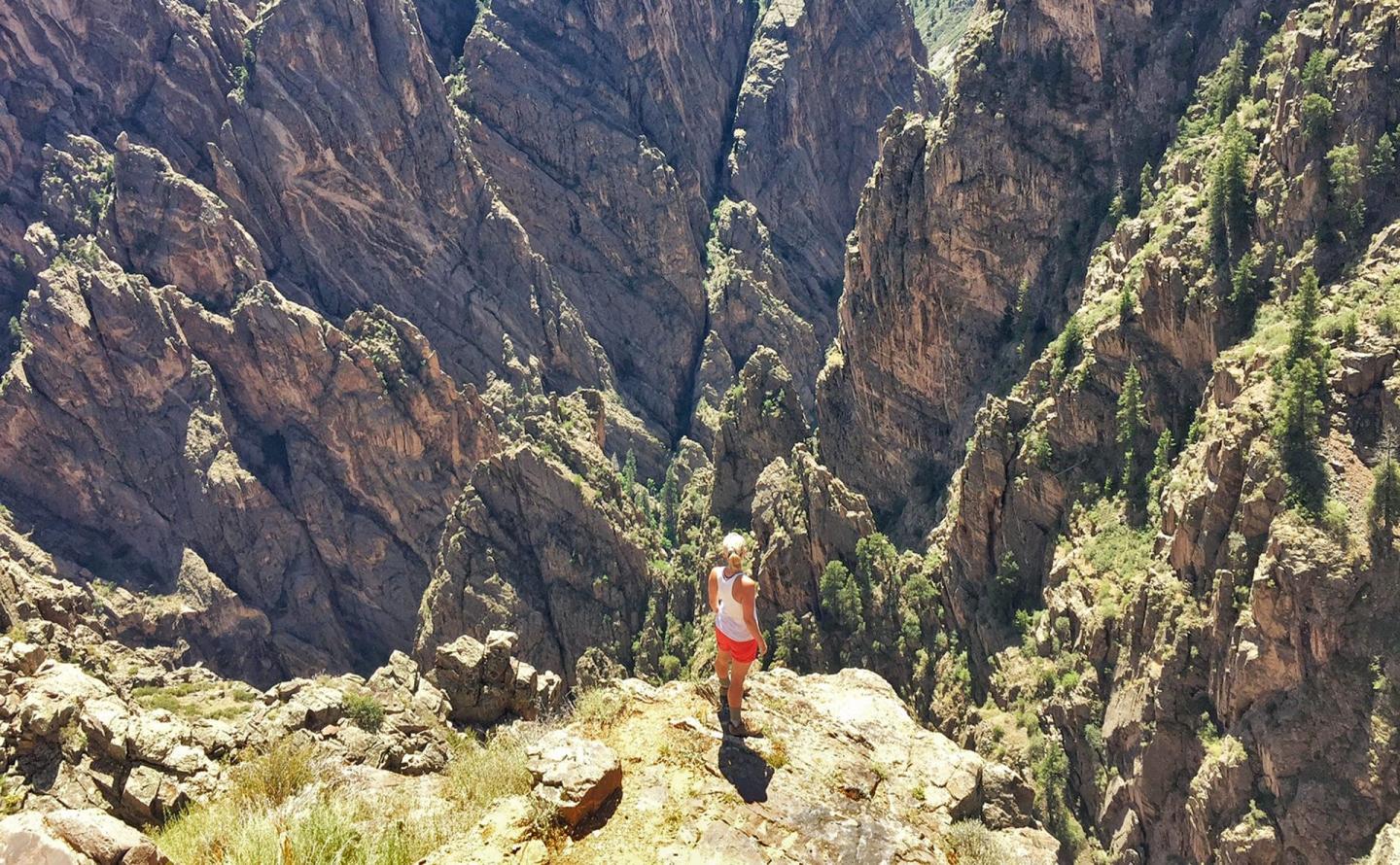 Person standing on a cliff edge, surrounded by steep, rocky canyon walls.