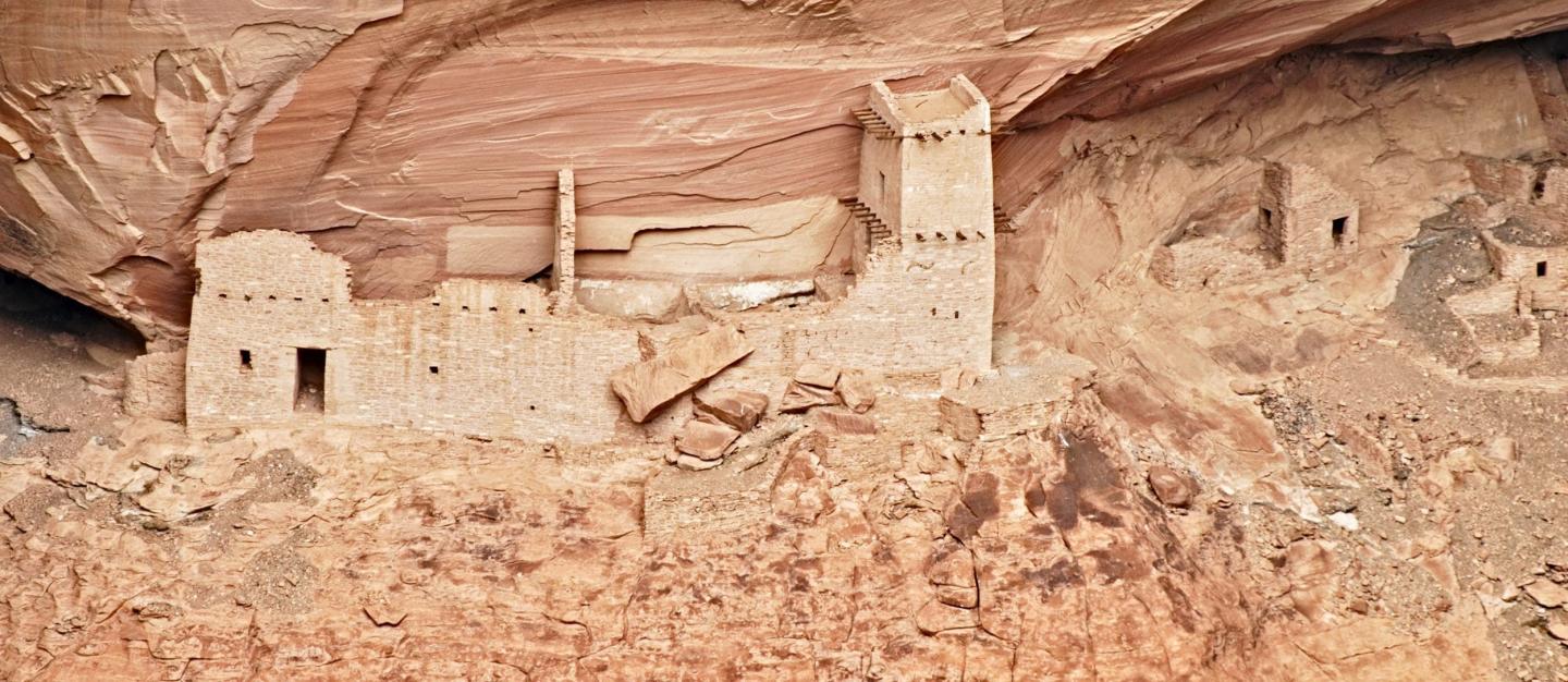 Ancient cliff dwellings under a red rock overhang.