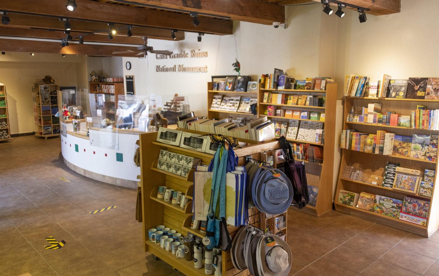 Gift shop interior with shelves of books, souvenirs, and hats. Warm lighting and wooden beams.