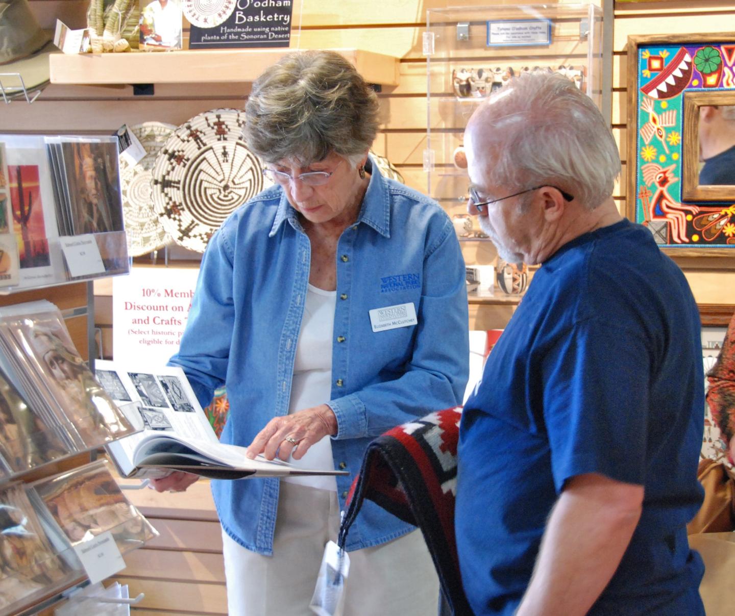 Elderly woman showing a book to an older man in a shop.