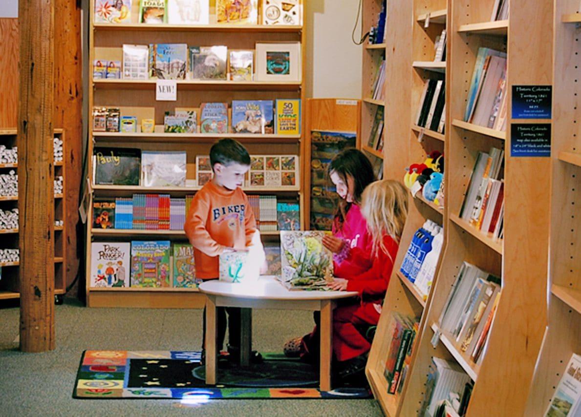 Children reading books at a small table in a cozy library setting.
