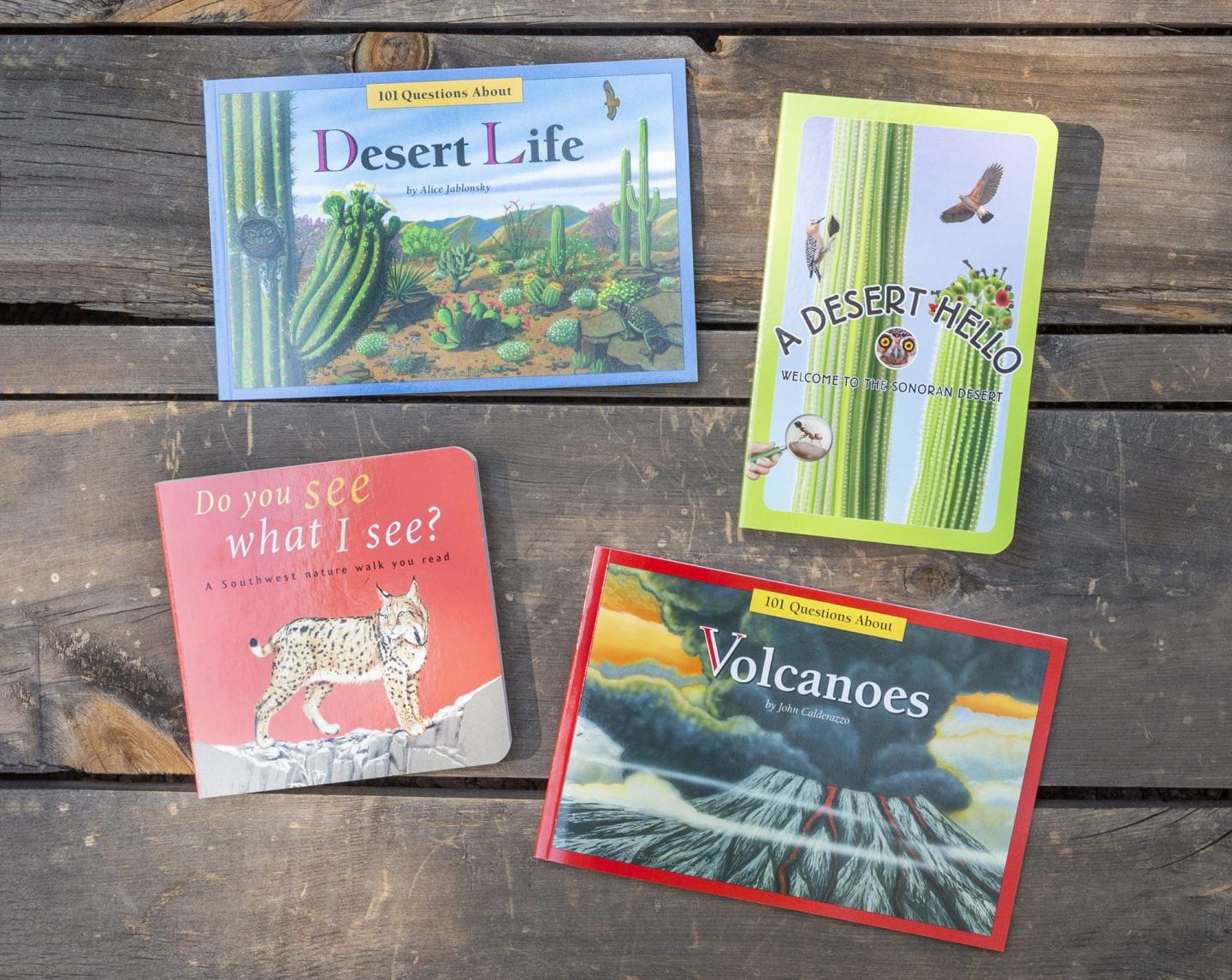 Four nature-themed books on a wooden table.