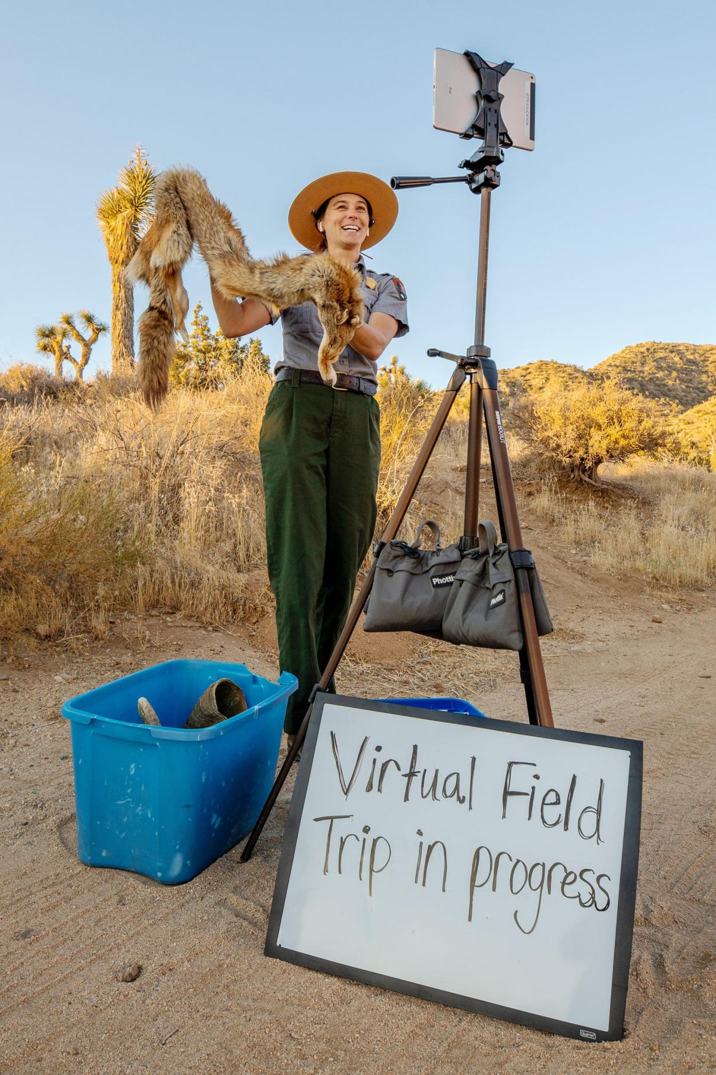 A park ranger holds a fox pelt during a virtual field trip outdoors.