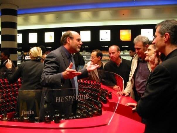 Man gesturing while talking to a group around a red counter in a store.