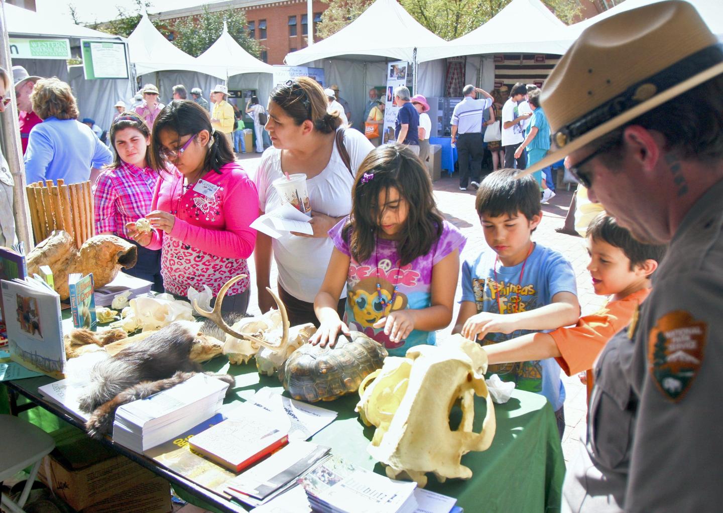 Children exploring animal exhibits at an outdoor educational event.