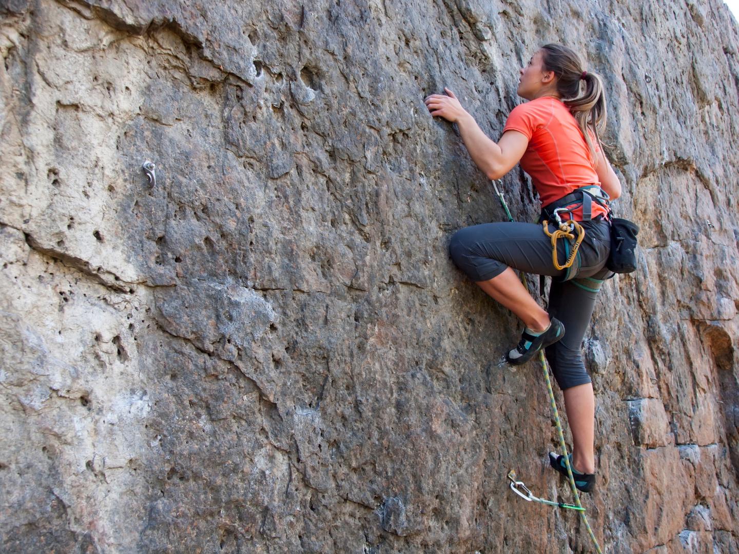 Woman rock climbing on a textured cliff.
