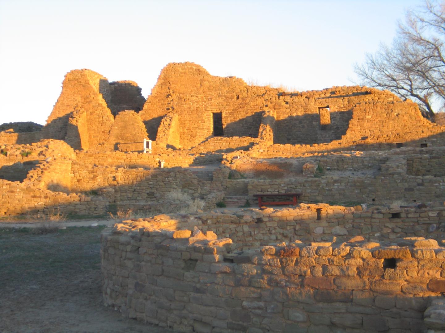 Aztec Ruins bathed in golden sunlight with a clear sky.