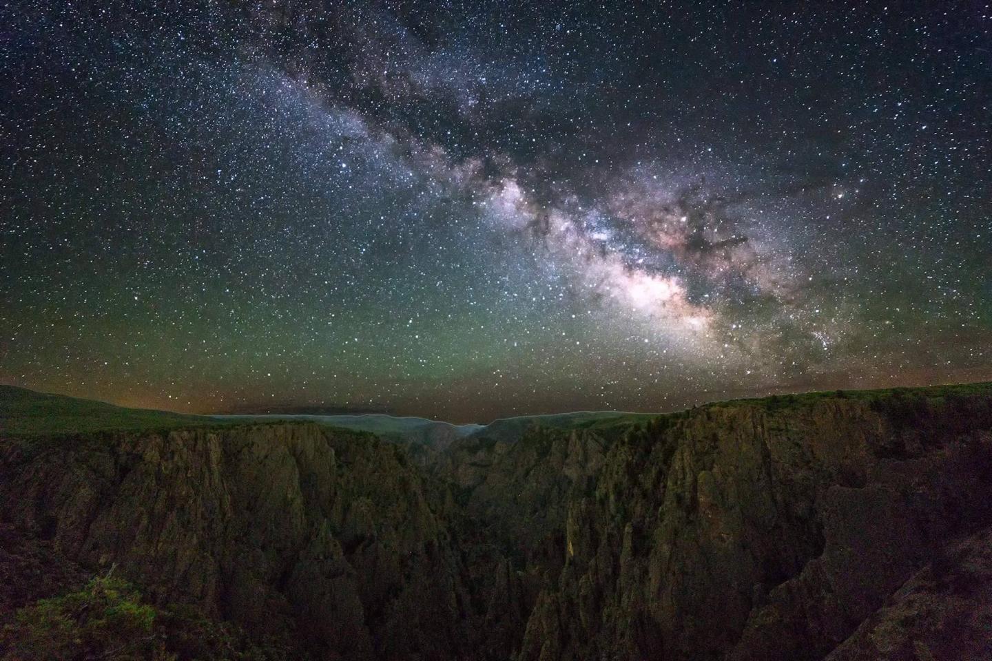 Starry night sky over a rocky canyon landscape at Black Canyon of the Gunnison..