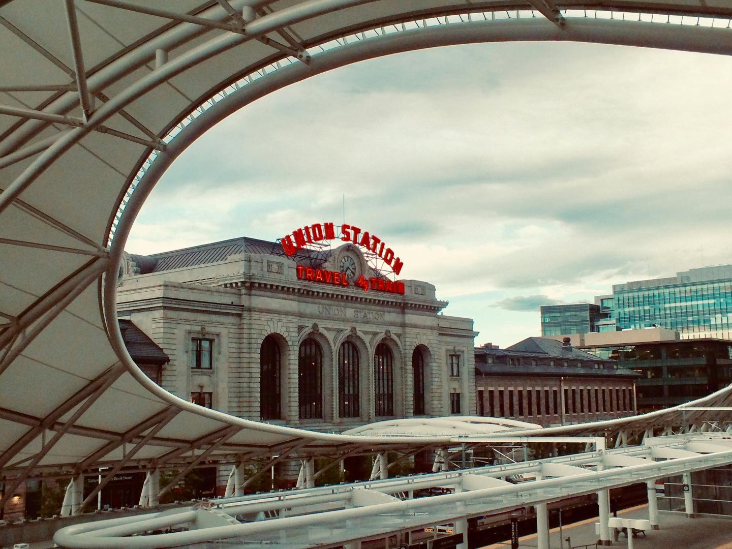 Union Station building framed by modern architecture, under a cloudy sky.