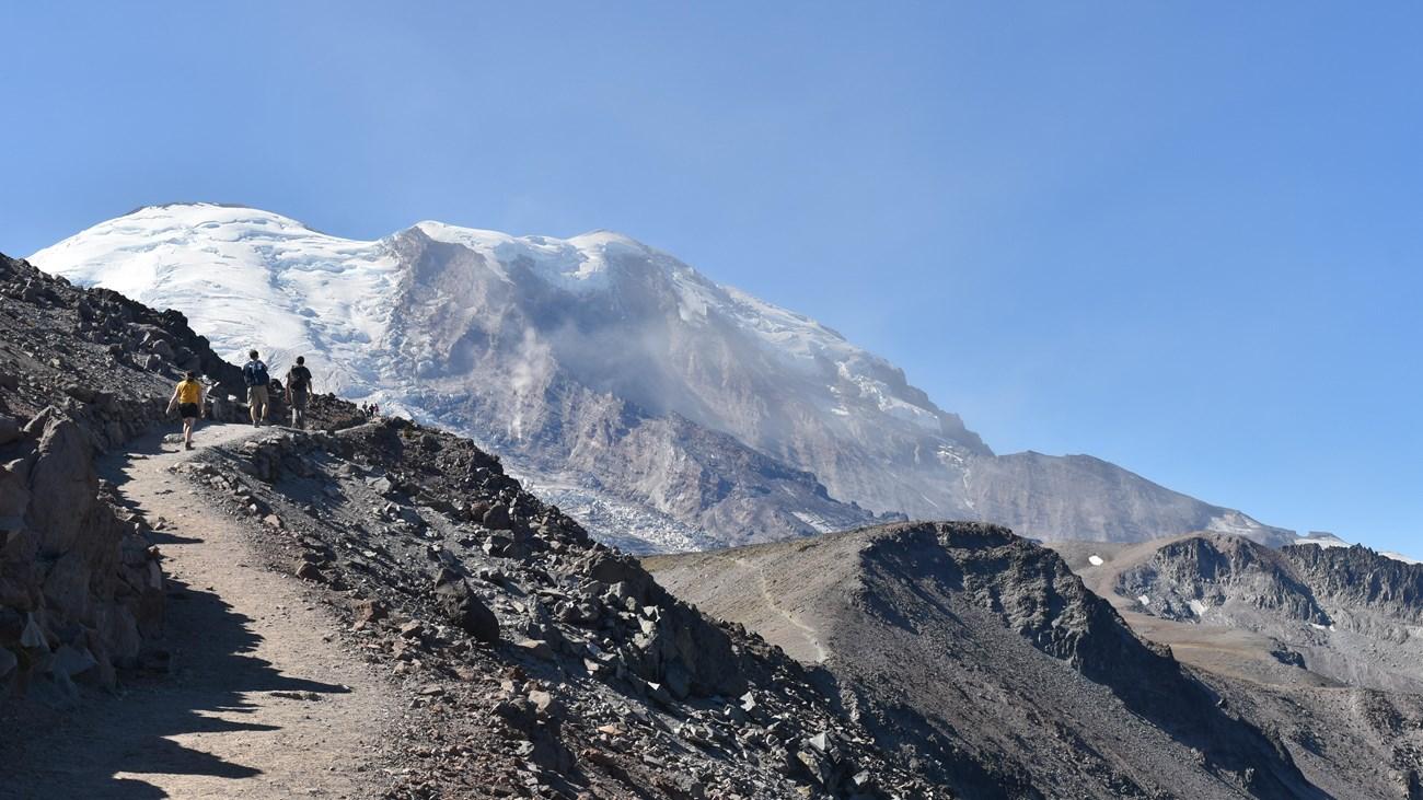 Burroughs Mountain Trail with hikers beneath a snowy peak.