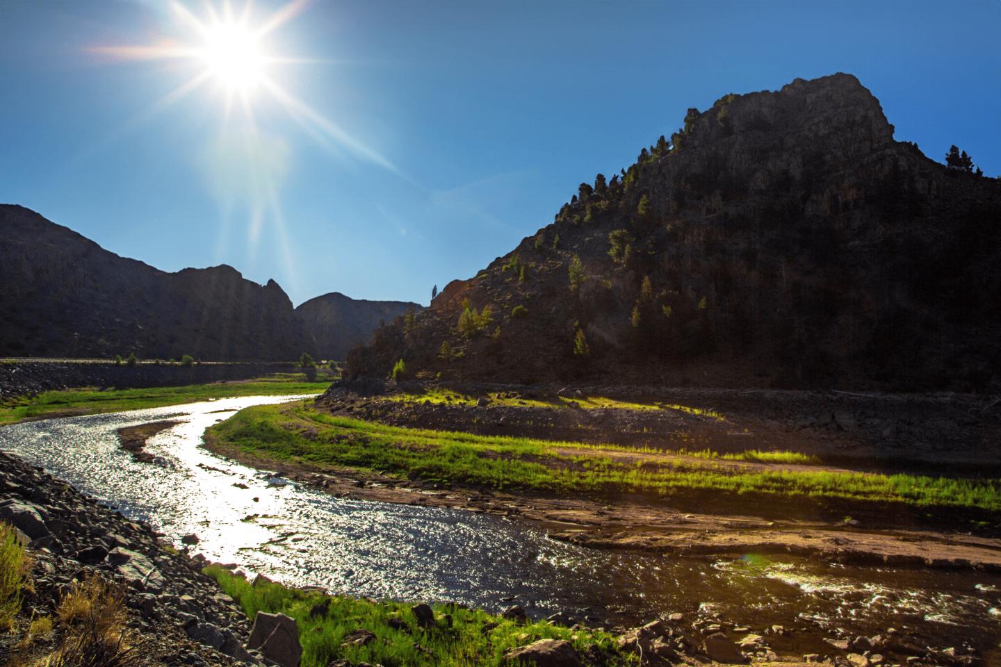 Curecanti river winding around a sunlit mountain under a clear blue sky.