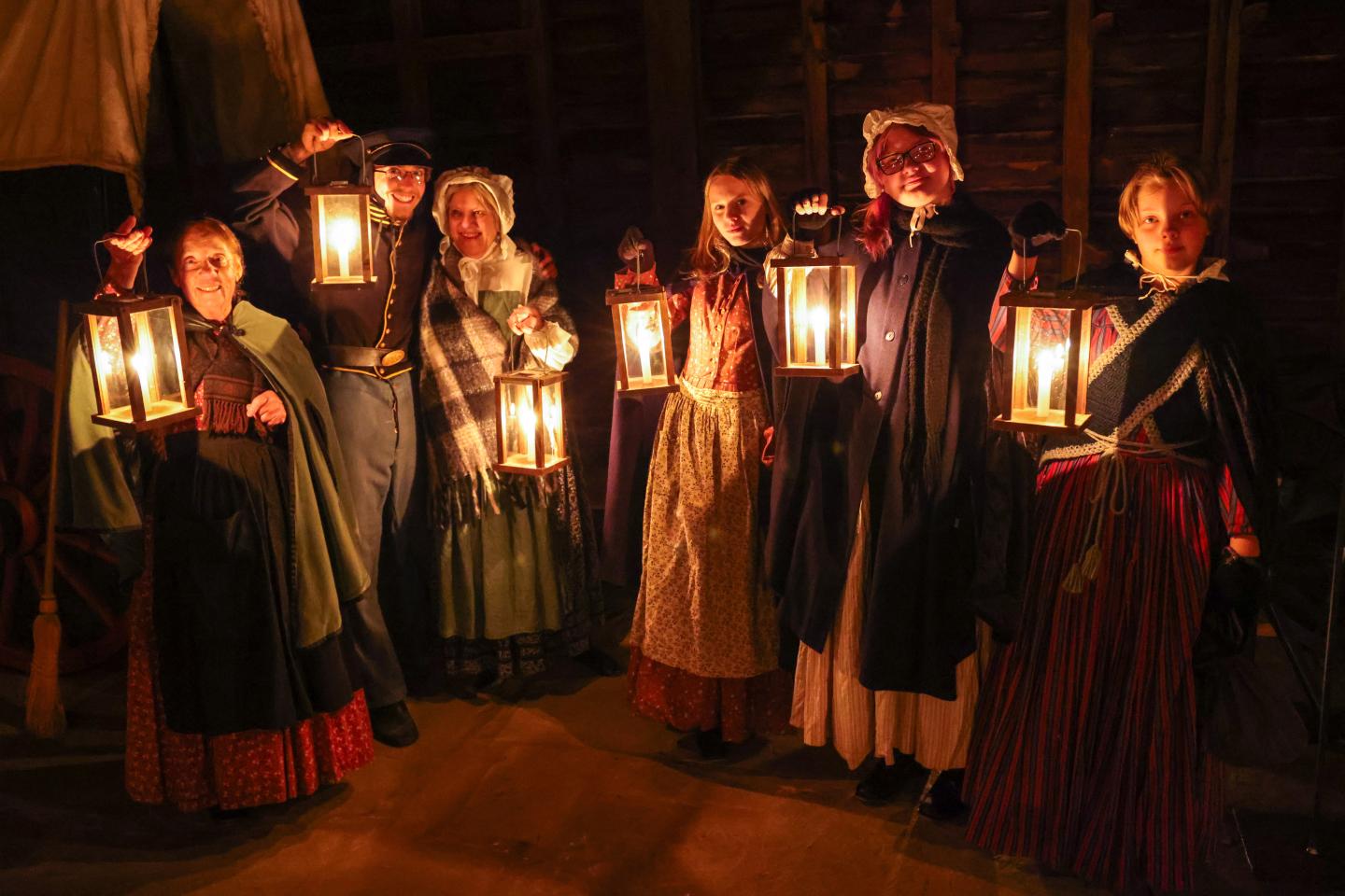 Group in historical costumes holding lanterns in a Candlelight Tour at Fort Scott National Historic Site.