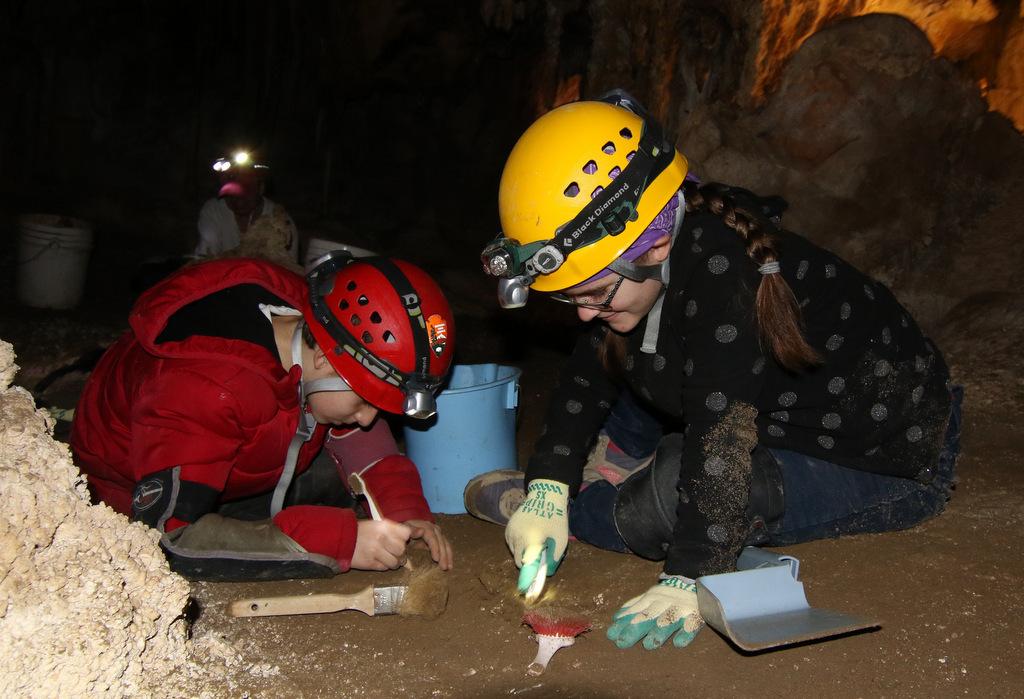 Two researchers in helmets examining items in a cave in Great Basin National Park.