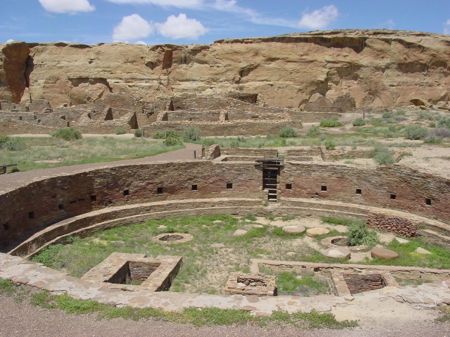 Ancient stone ruins with circular structure, set against a rocky desert landscape.