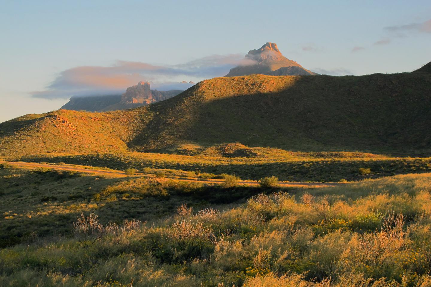 Chisos mountains at sunset, shadowed hills, and clouded sky.