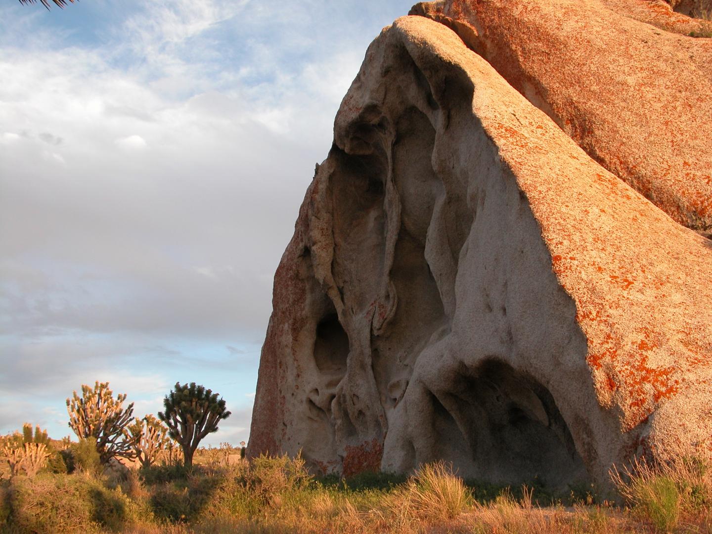 Cima Dome formation with red hues and eroded cavities, set in a desert landscape.