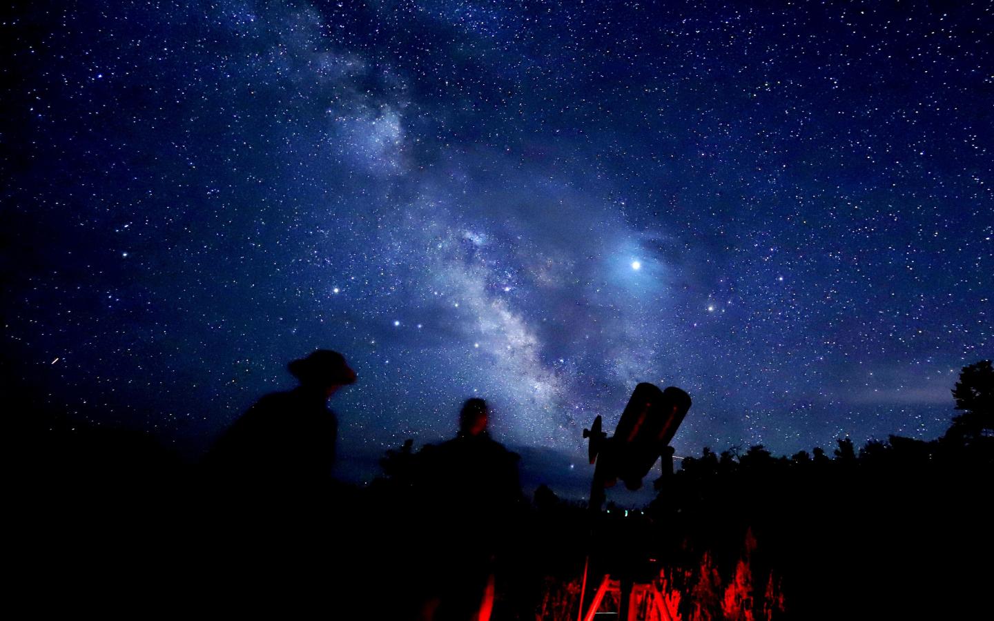 Stargazers silhouetted against a starry night sky with the Milky Way.
