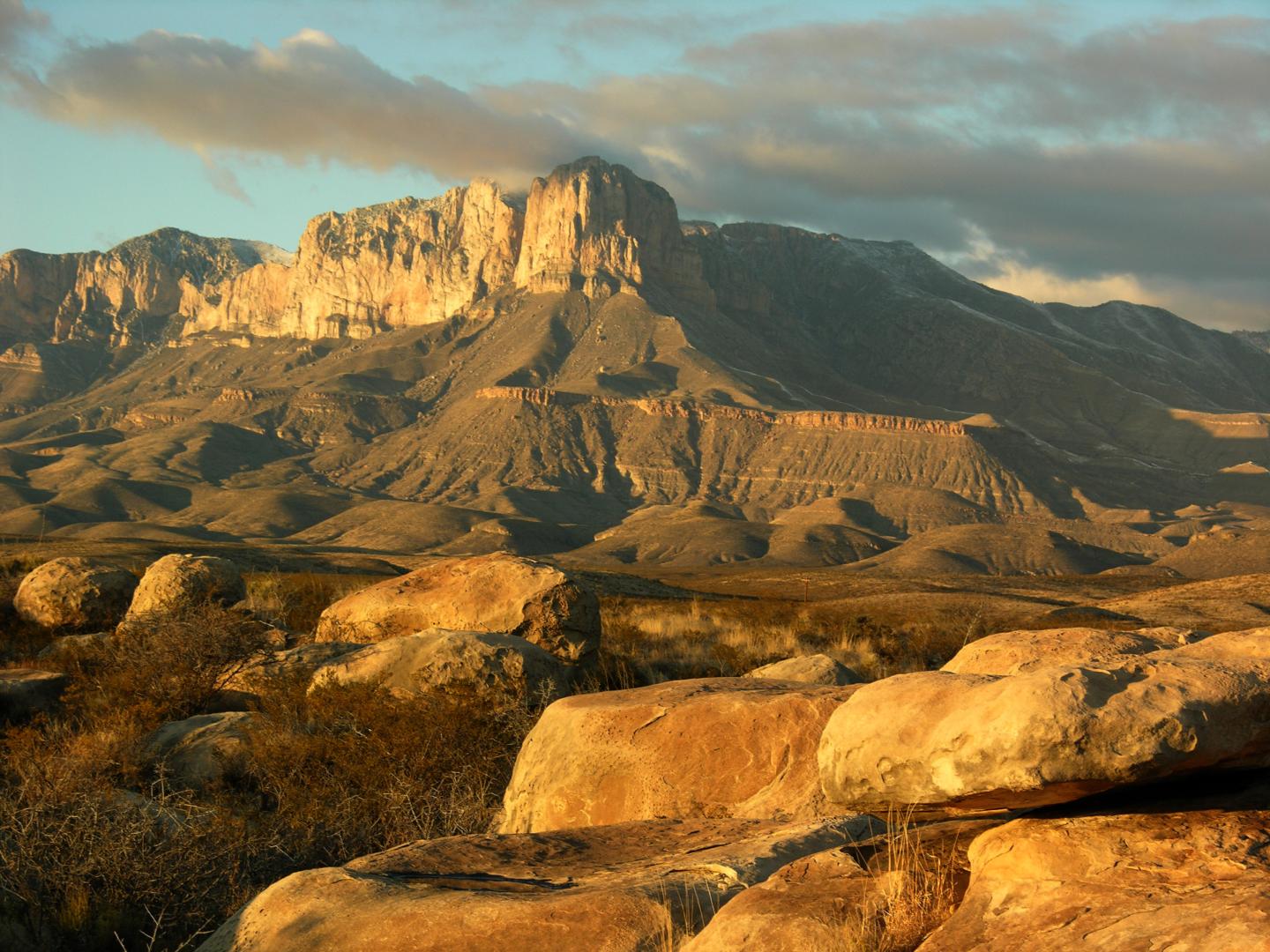 El Capitan landscape with rocky foreground, under a cloudy sky at sunset.