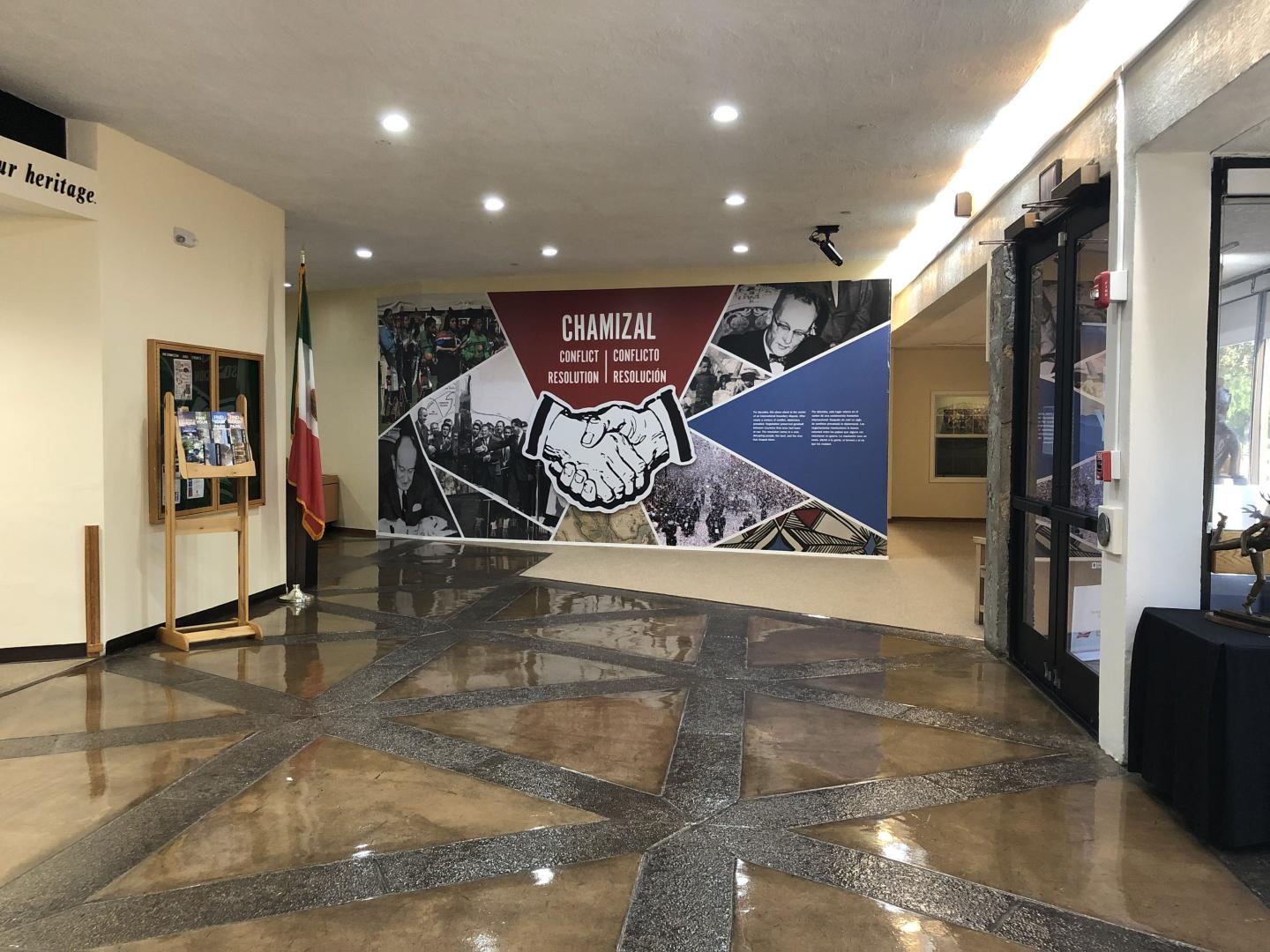 Visitor center with mural of a handshake, polished floor, and flag display.