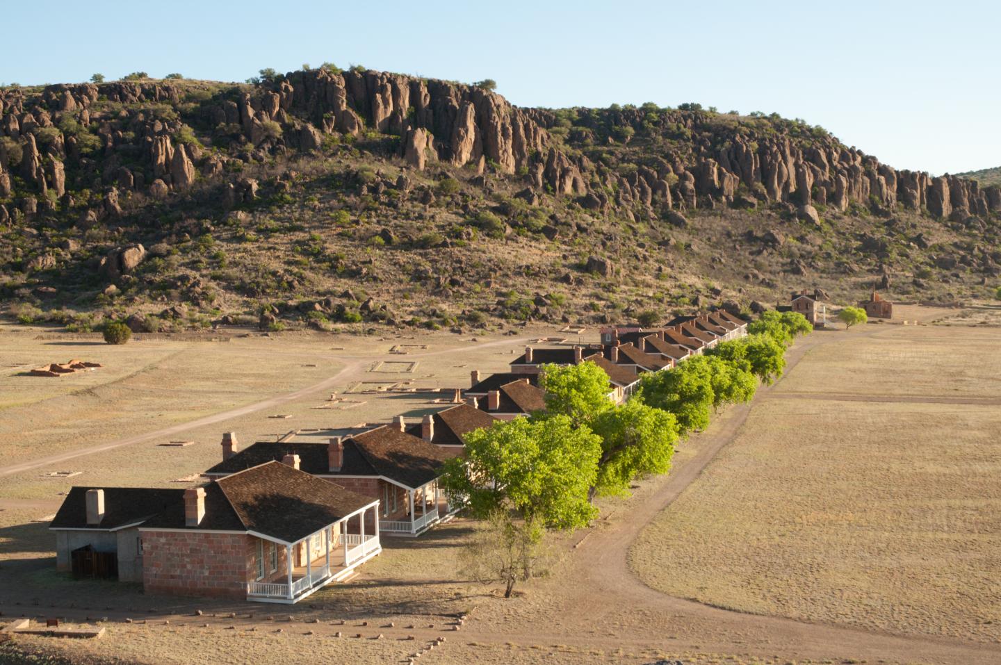 Fort Davis with green trees, set against rocky hills in a dry landscape.