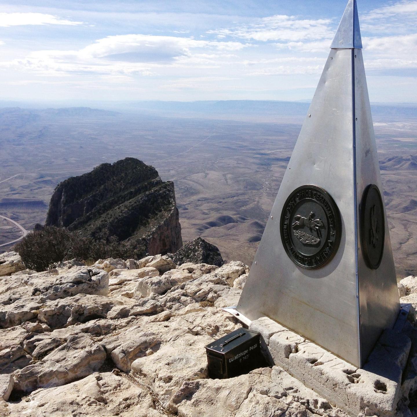 Monument on Guadalupe Peak, vast landscape in the background.
