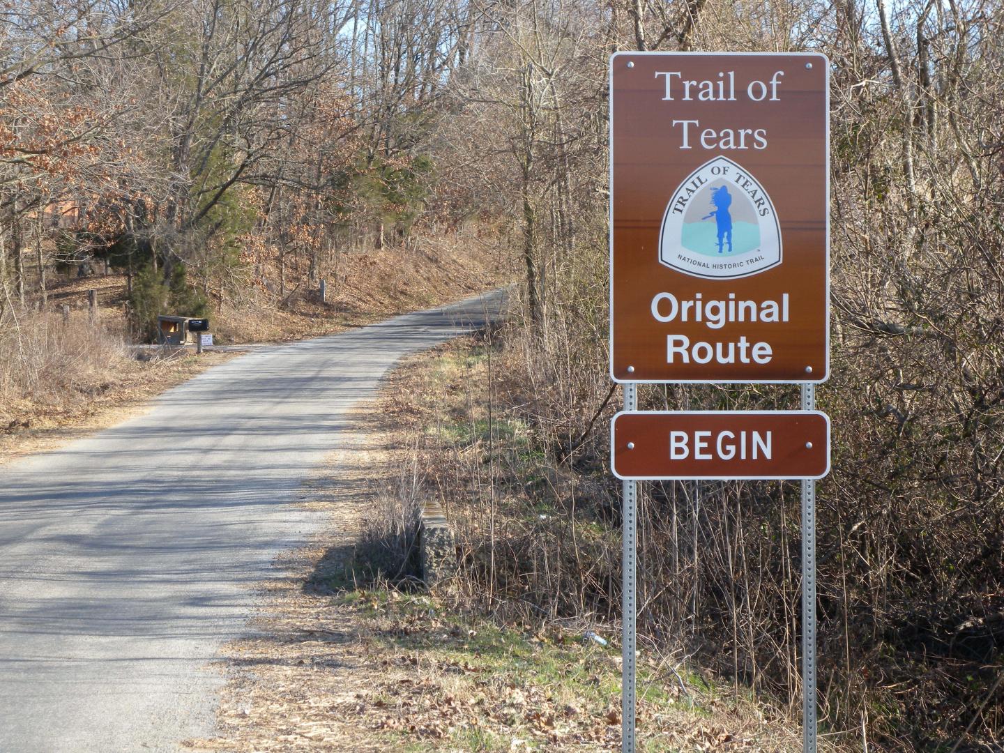 Trail of Tears sign marking the original route on a wooded path.