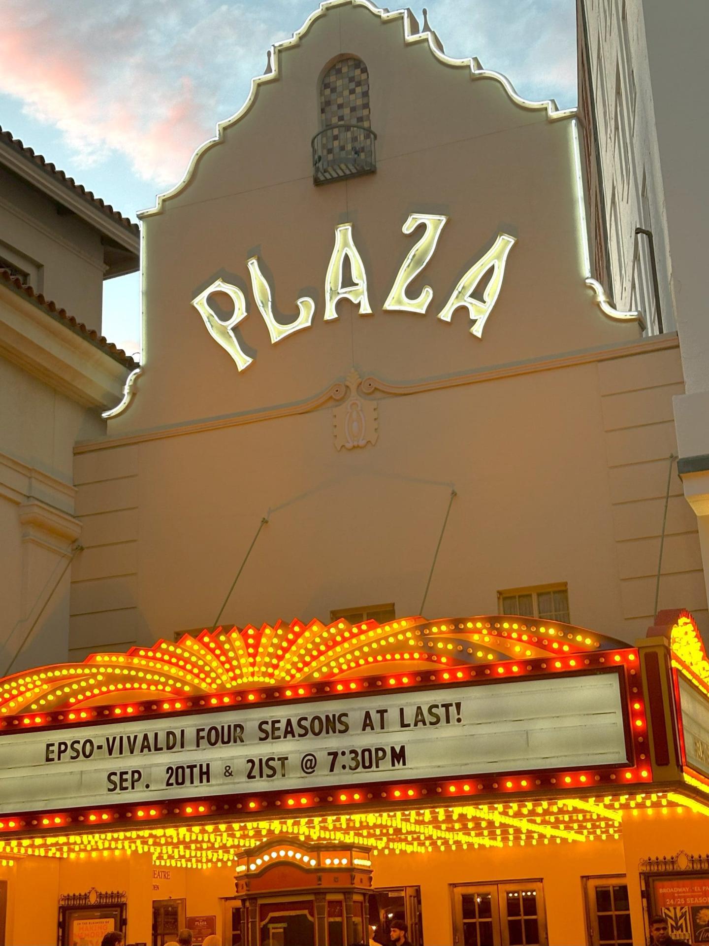 Plaza theater facade with bright marquee lights at dusk.