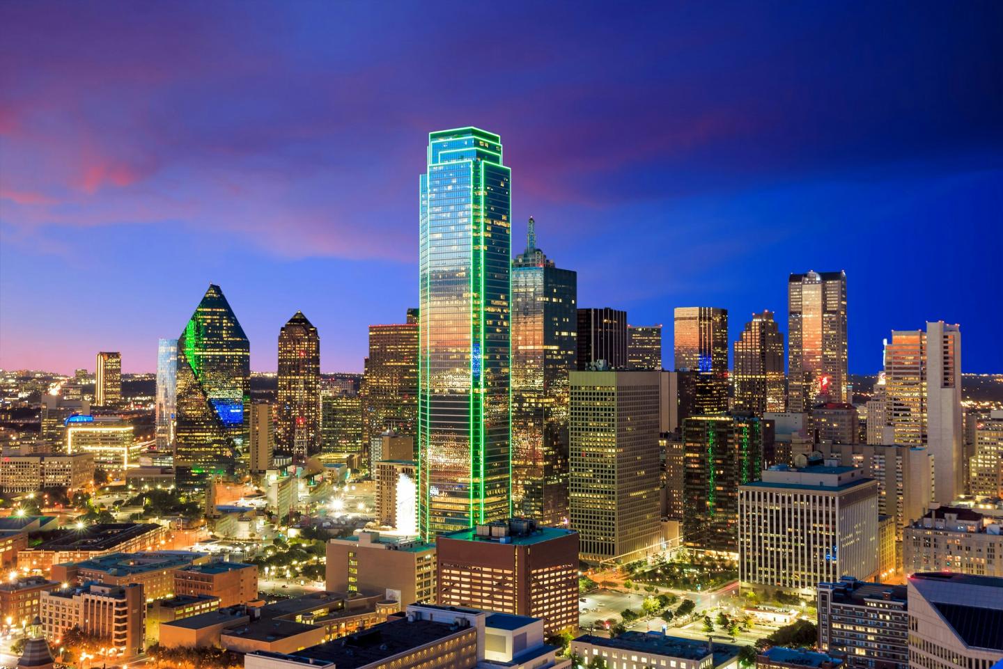 Dallas skyline at night, featuring illuminated skyscrapers.