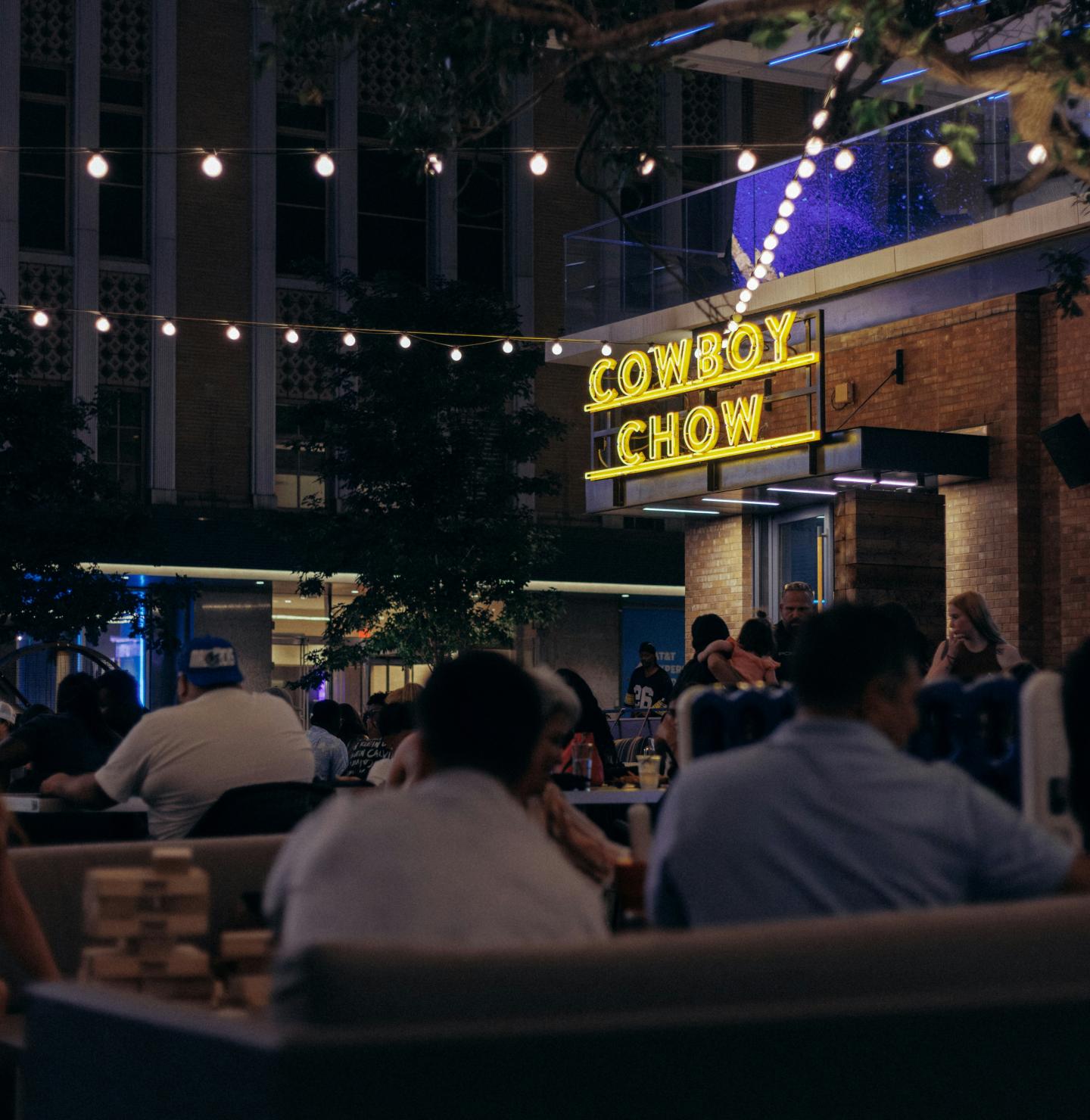 Nighttime outdoor restaurant with fairy lights and people dining.