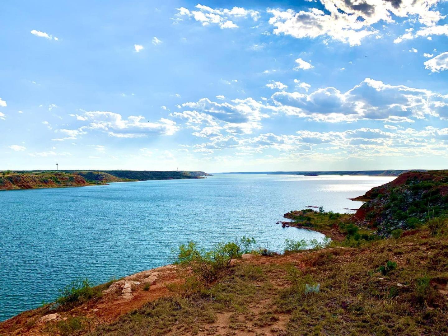 Serene lake under a bright blue sky with scattered clouds.