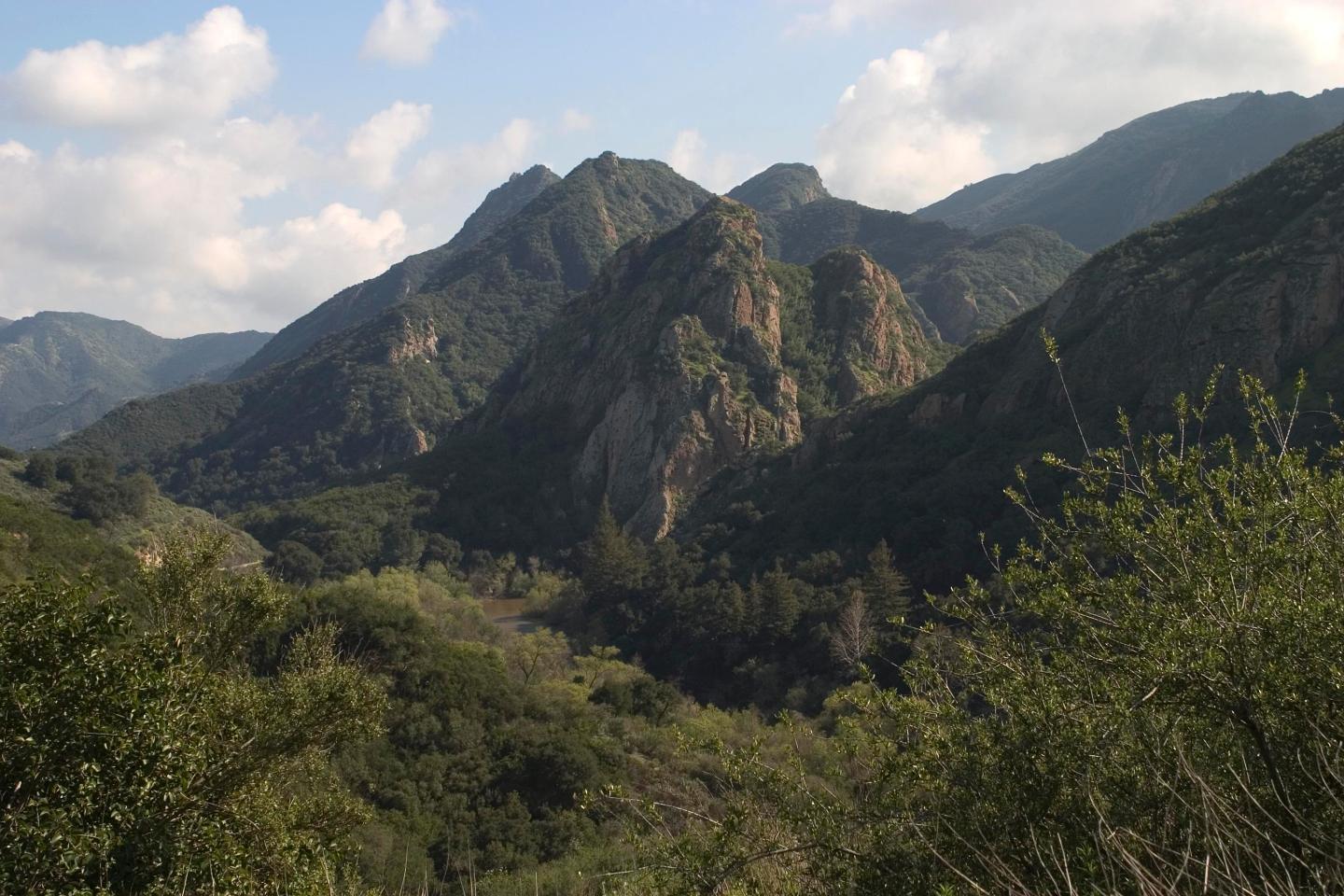 Malibu Creek State Park with green valleys under a partly cloudy sky.