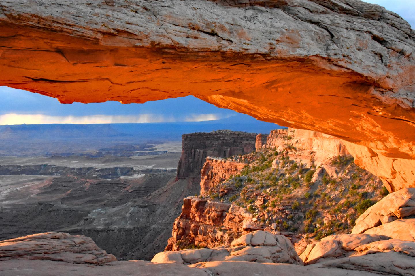 Sunrise at Mesa Arch, canyon landscape with glowing red rocks.