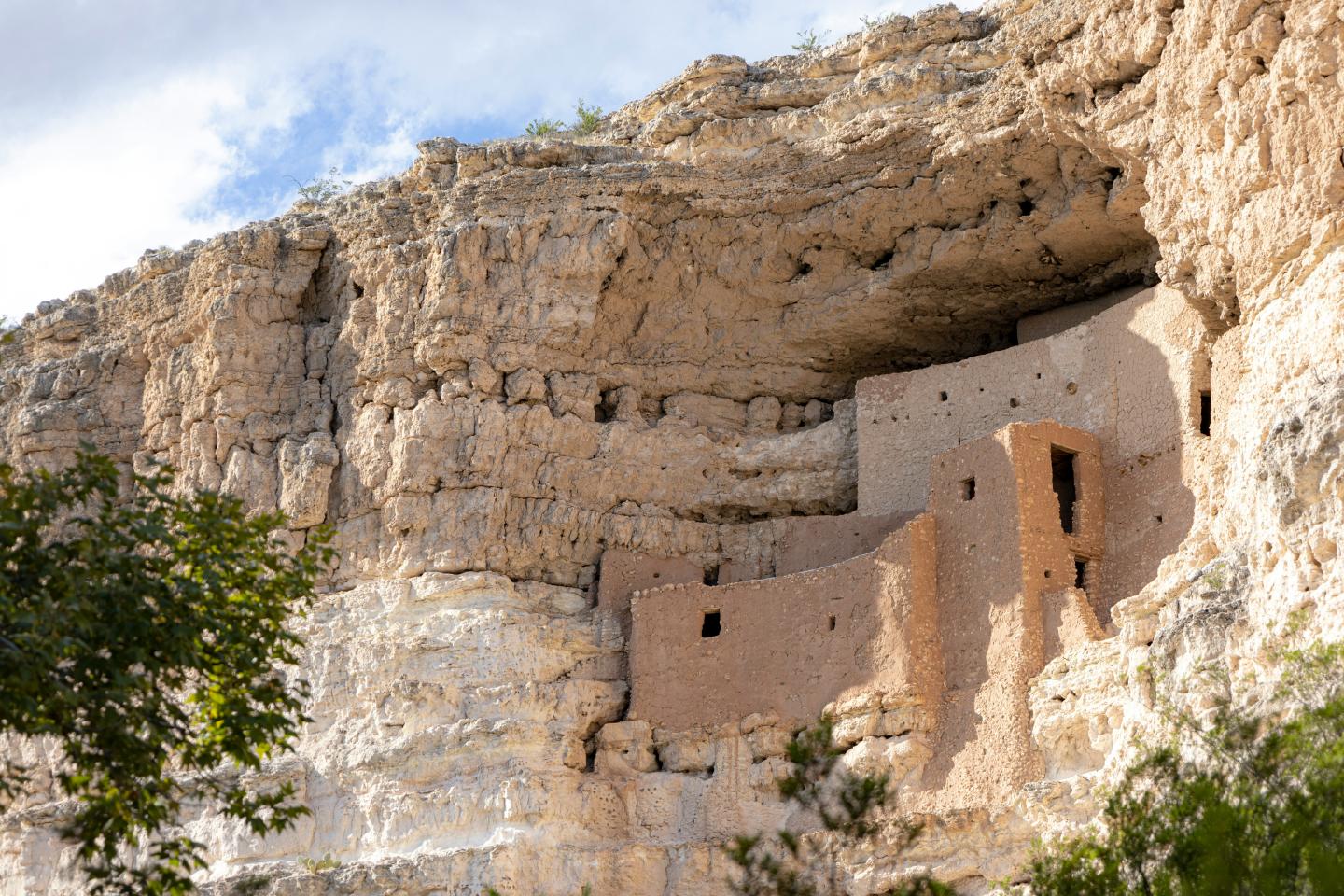 Montezuma Castle built into a rocky hillside under a blue sky.