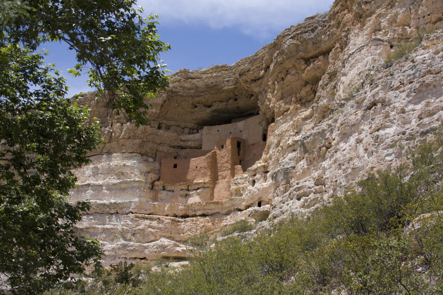 Montezuma Castle nestled in a rocky canyon under a clear blue sky.