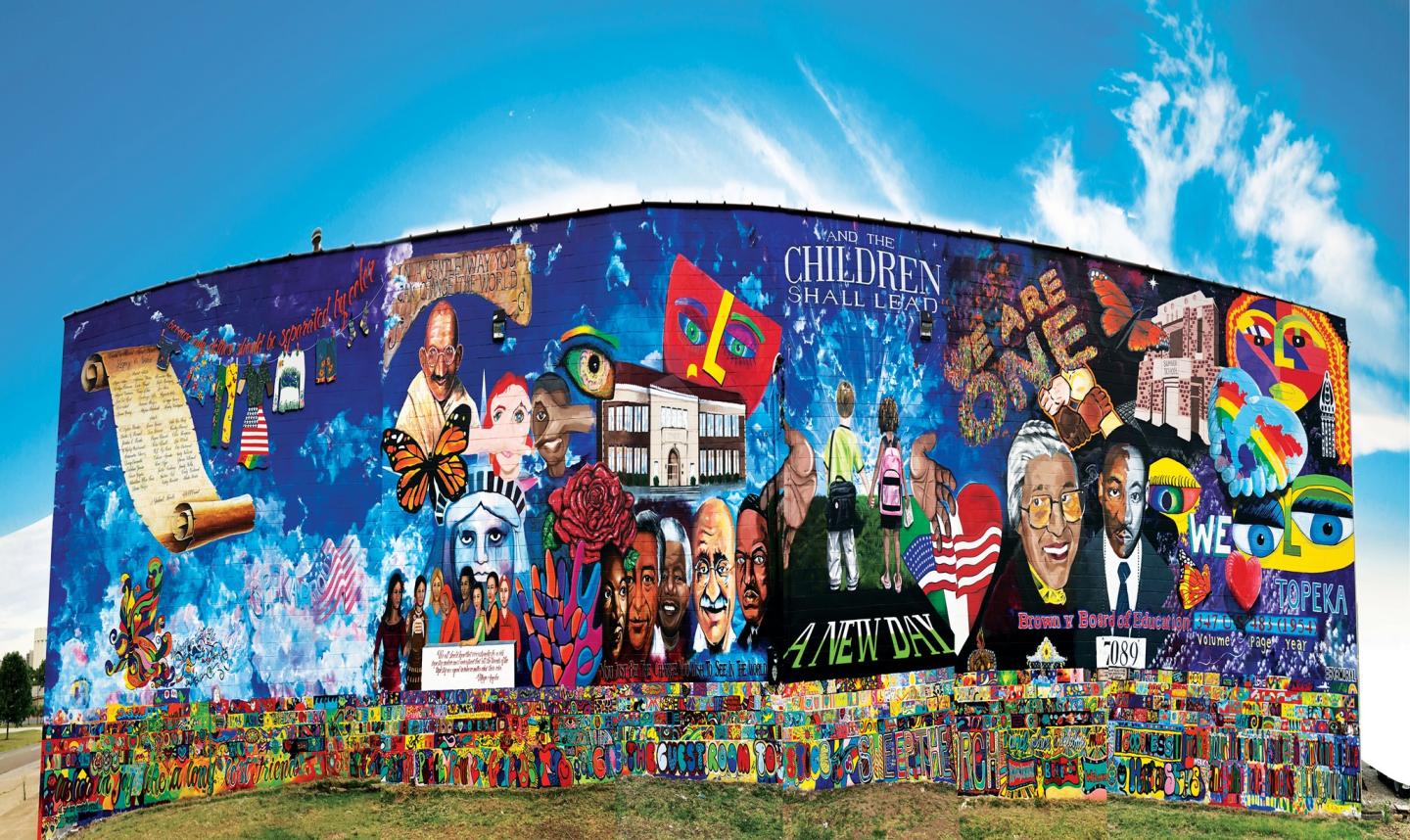 Colorful mural depicting diverse cultural elements and historical figures under a blue sky.