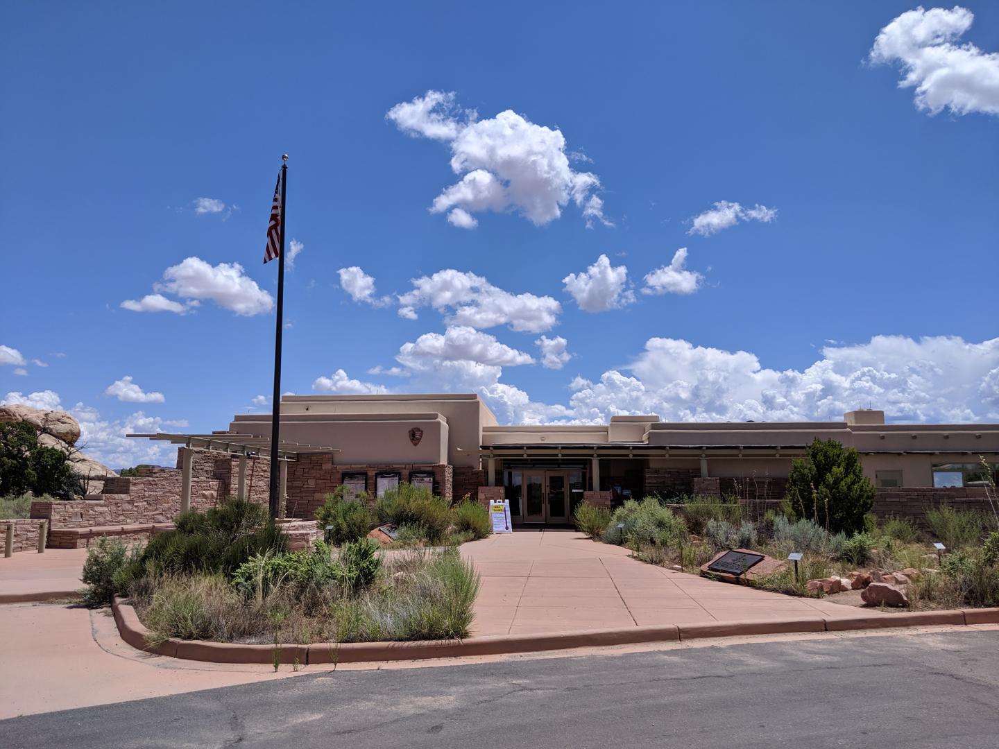 Needles Visitor Center with flagpole under a blue sky with clouds.