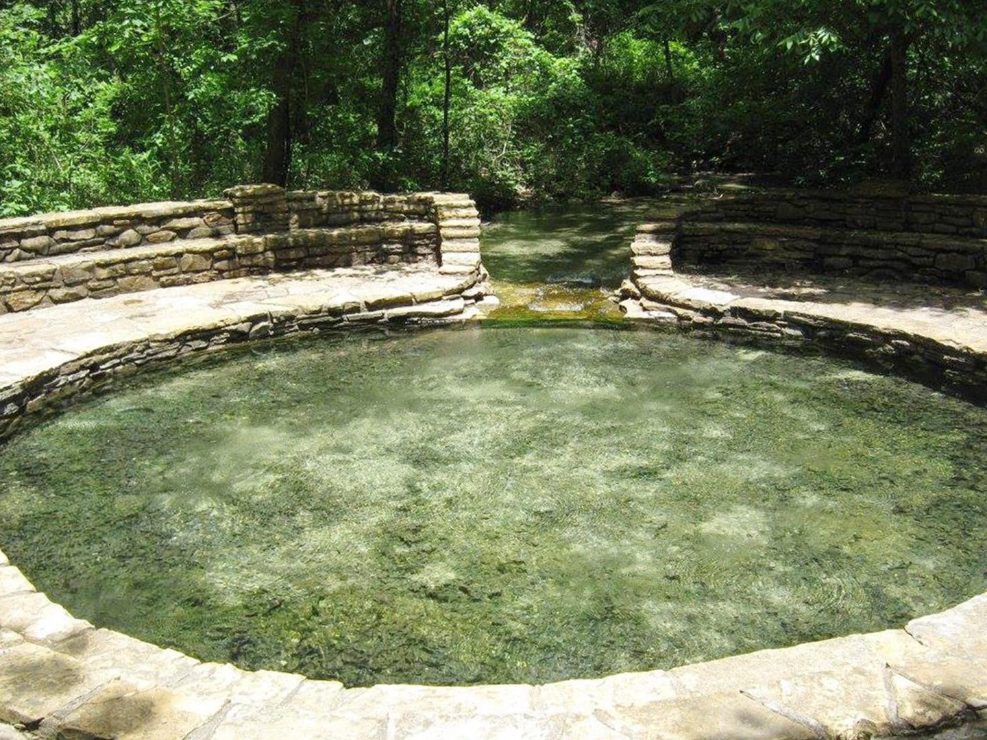 Stone-framed circular pool at Little Niagara surrounded by trees.