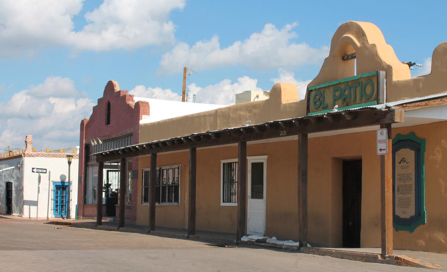 Historic adobe buildings under a blue sky with scattered clouds.