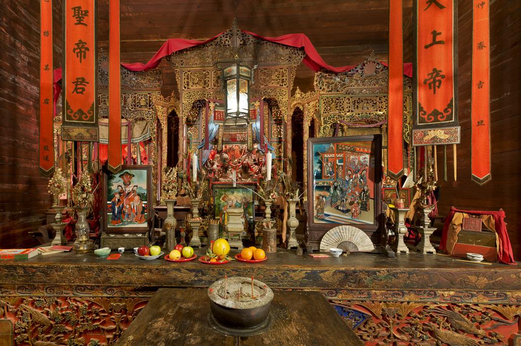 Elaborate altar with red banners, offerings, and ornate decorations.