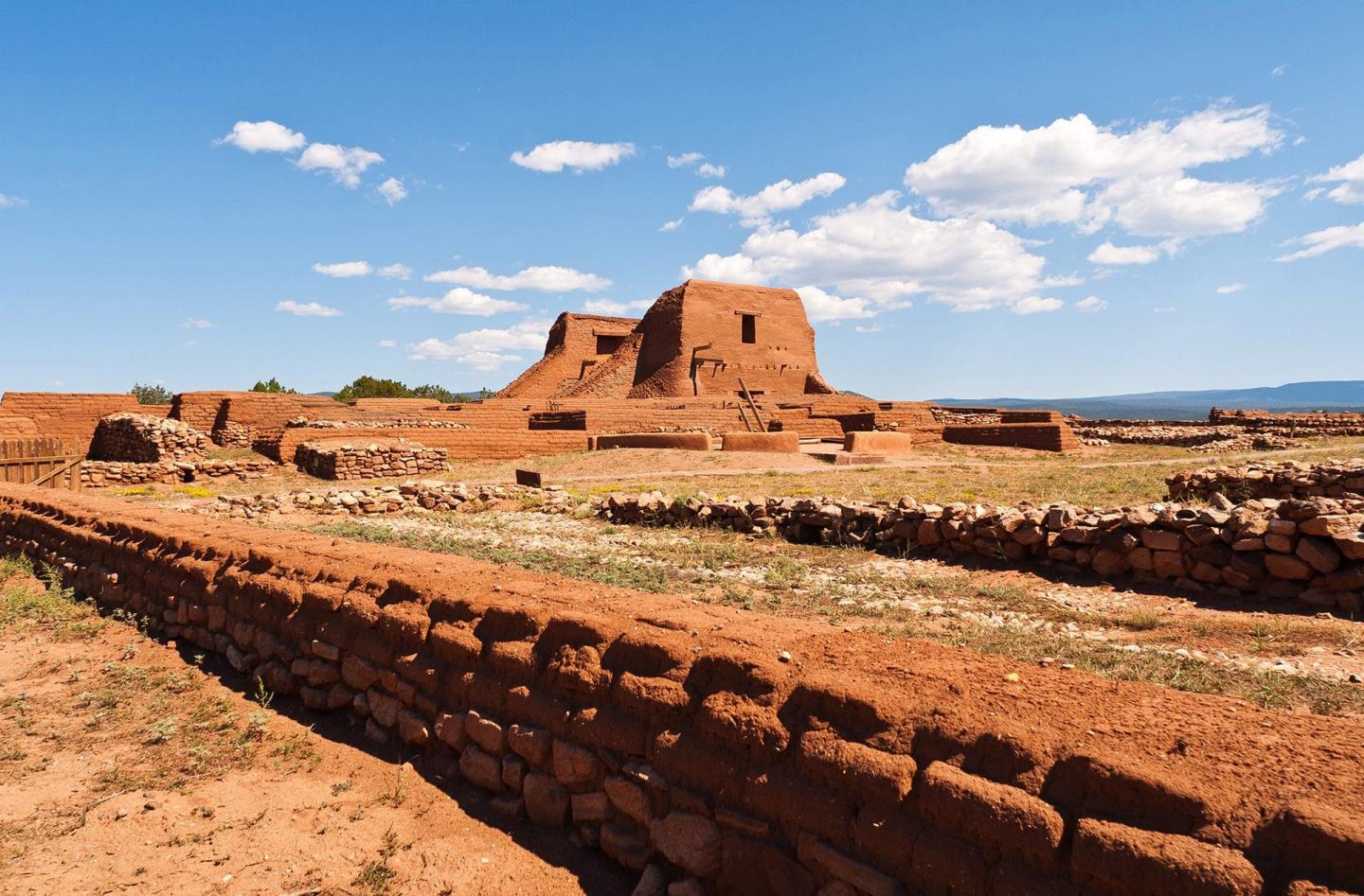 Ancient adobe ruins under a bright blue sky with scattered clouds.