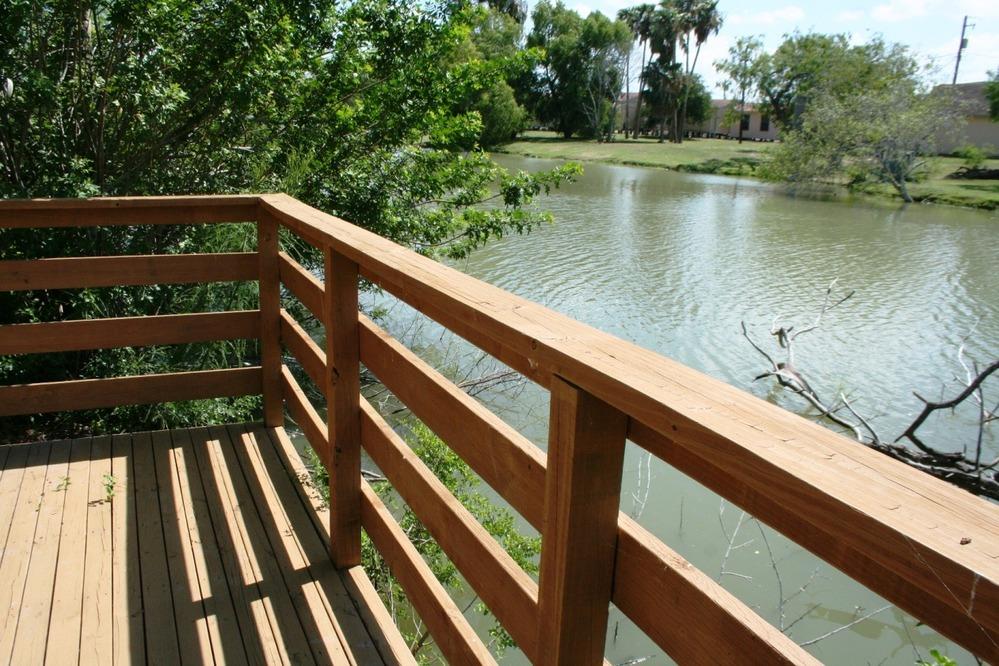 Wooden deck overlooking Resaca waterfront with trees and greenery.