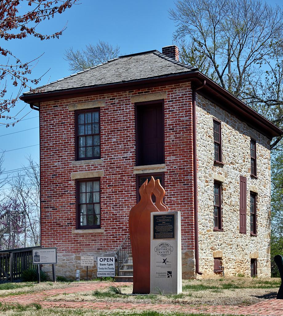 Ritchie House building with a statue in front, surrounded by trees.