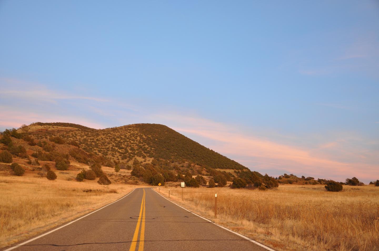 Open road leading to Capulin under a blue and pink sky.