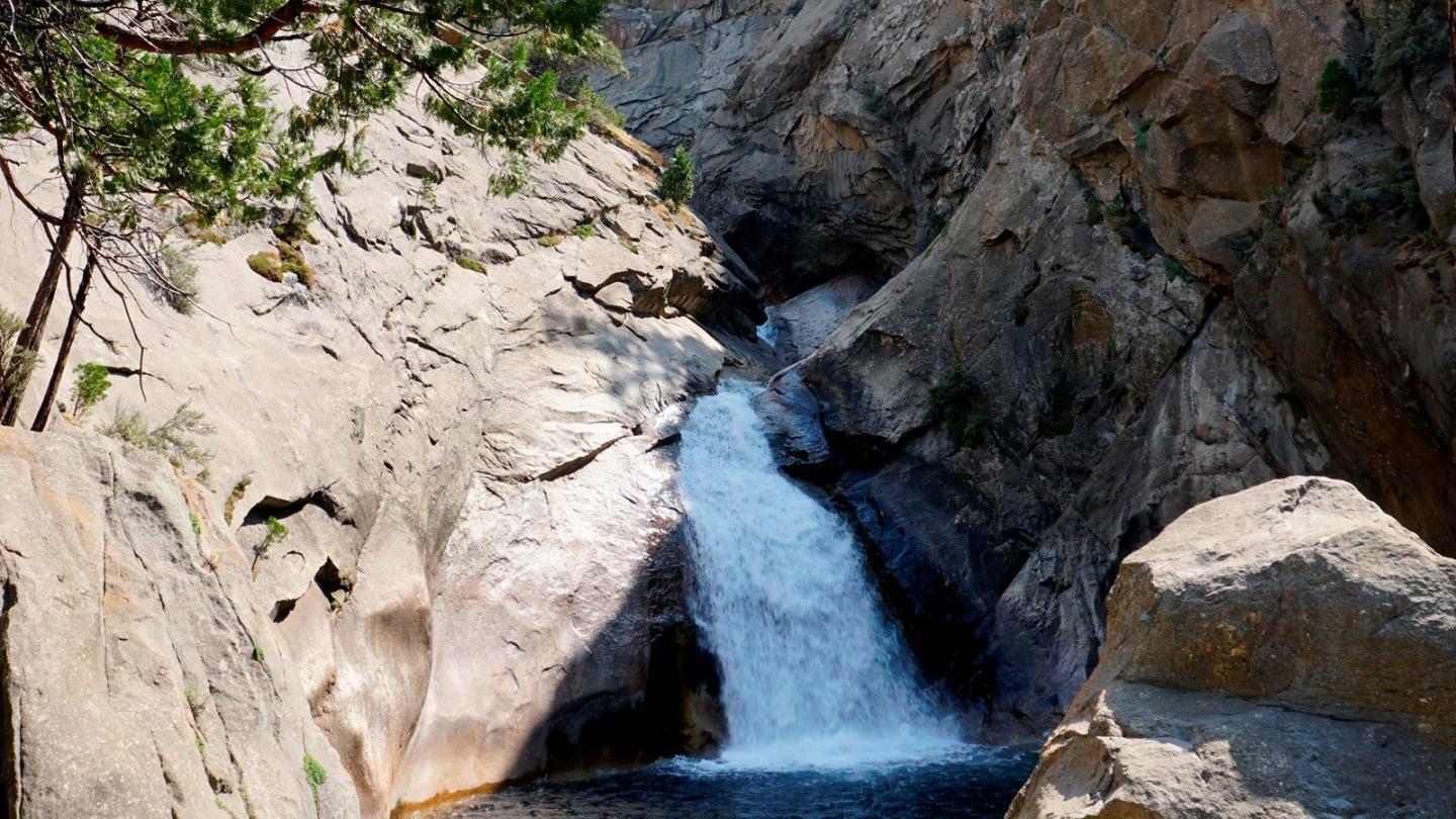 Waterfall cascading between rocky cliffs with a small pool at the base.